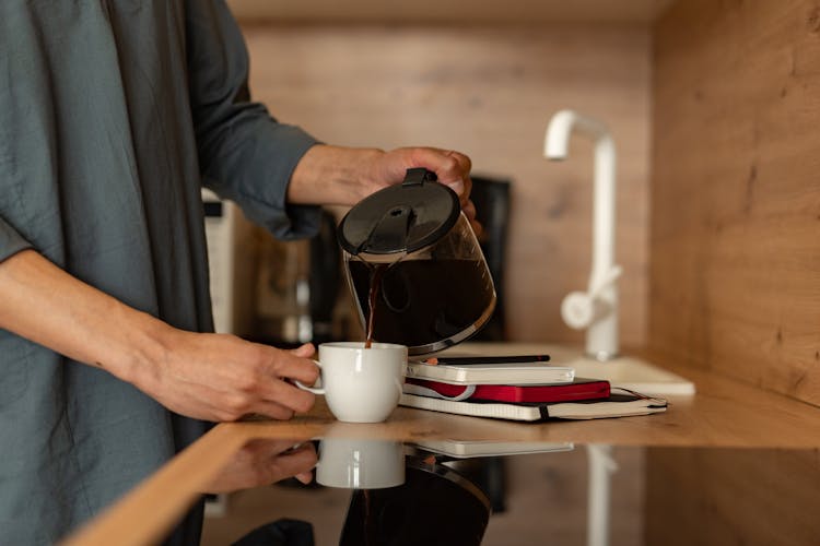 Person Pouring Coffee On A White Mug 