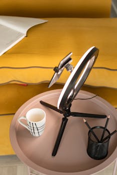Cozy workspace featuring a ring light, smartphone stand, and coffee cup on a stylish tray.