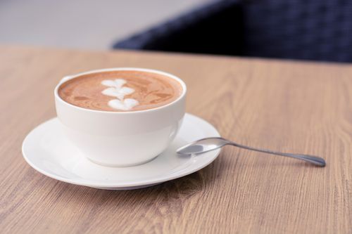 Free A cup of cappuccino with beautiful latte art served on a wooden table. Stock Photo