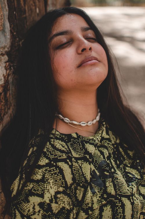Free Portrait of a woman enjoying a serene moment outdoors in Morocco, eyes closed, wearing necklace. Stock Photo