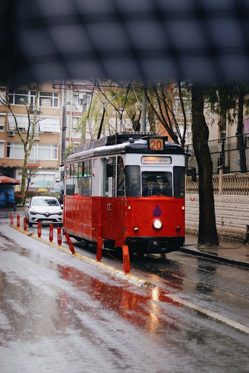 Modern tramway driving along wet asphalt road through town in daytime in city