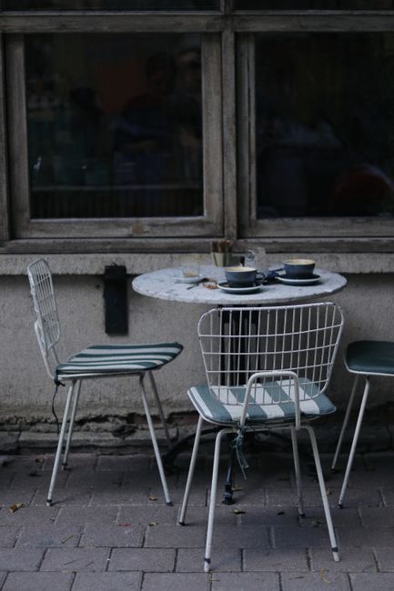 Dirty dishes on table near shabby chairs in old town cafe by window on pavement