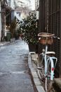 Bicycle with basket parked on paved walkway near old building with green plant on street in city