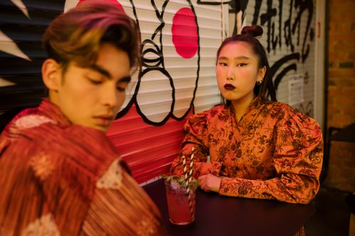 Free Stylish couple photographed in a modern café with vibrant graffiti backdrop. Stock Photo
