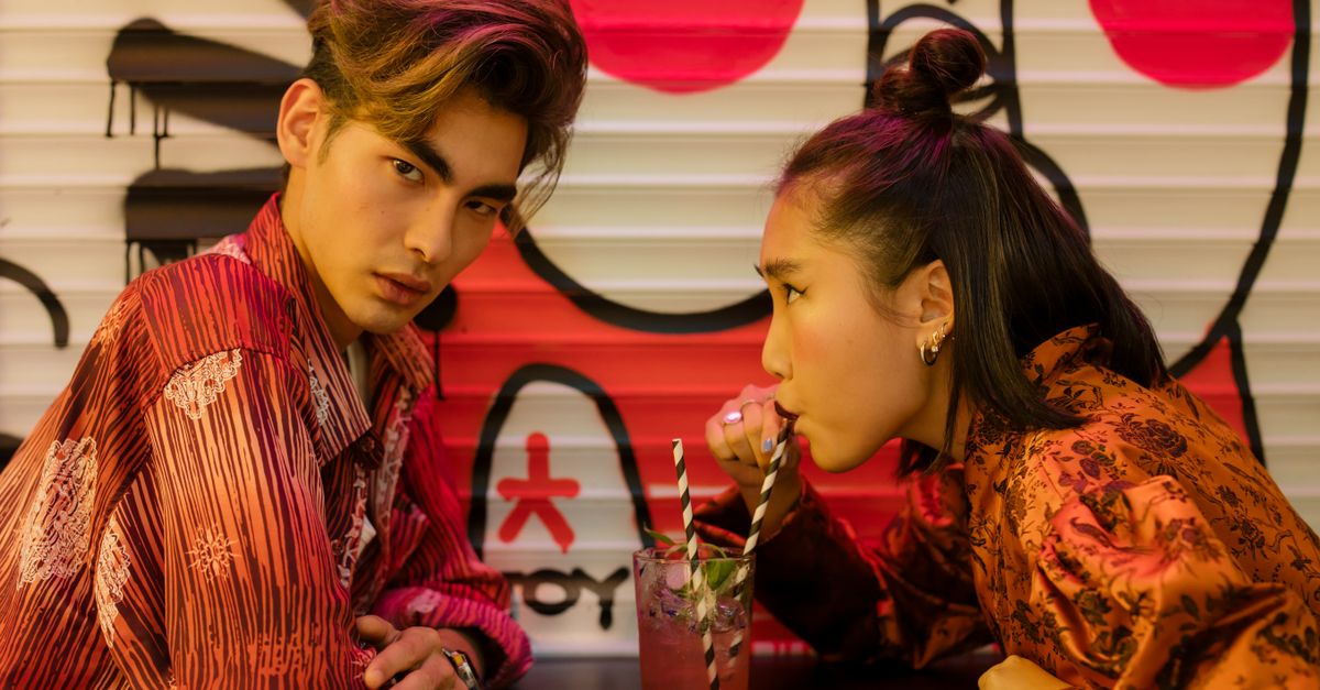 Stylish couple sharing a cocktail in a vibrant graffiti-themed café, capturing a modern romantic vibe.