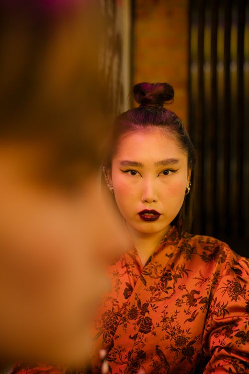Free Portrait of an Asian woman with dark lipstick in a dimly lit restaurant, showcasing fashion and confidence. Stock Photo