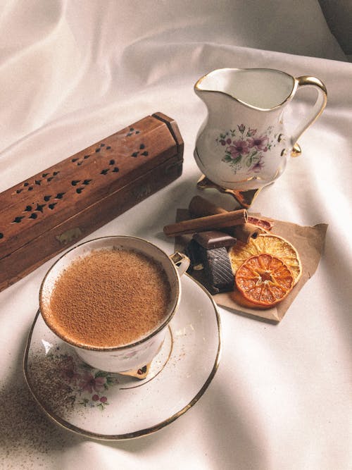 Cup of cacao with aromatic cinnamon near candied fruit