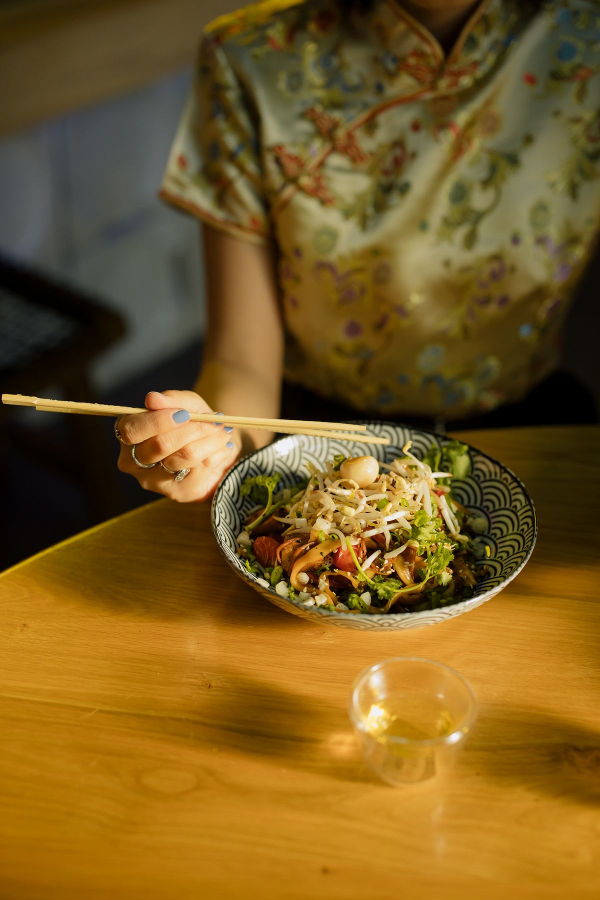 Person eating noodles with chopsticks in a Cantonese restaurant