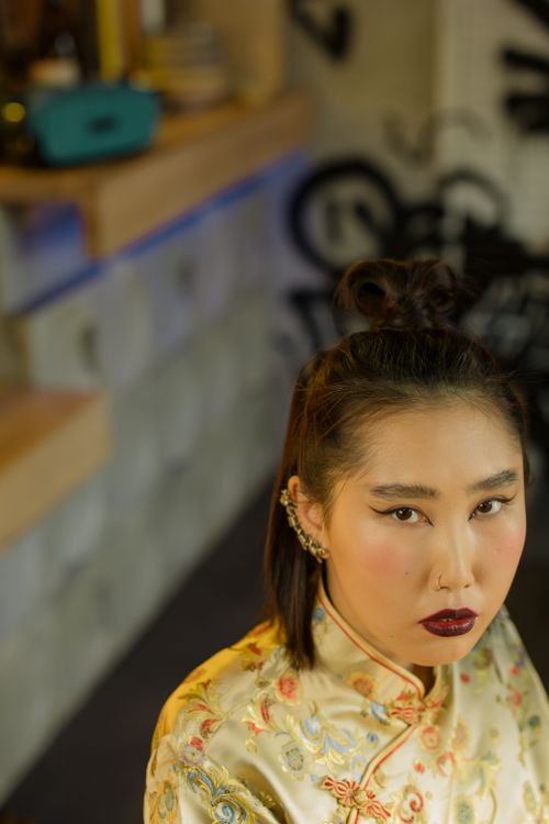 Free Stylish portrait of an Asian woman in a traditional silk dress indoors, showcasing elegant fashion and cultural attire. Stock Photo
