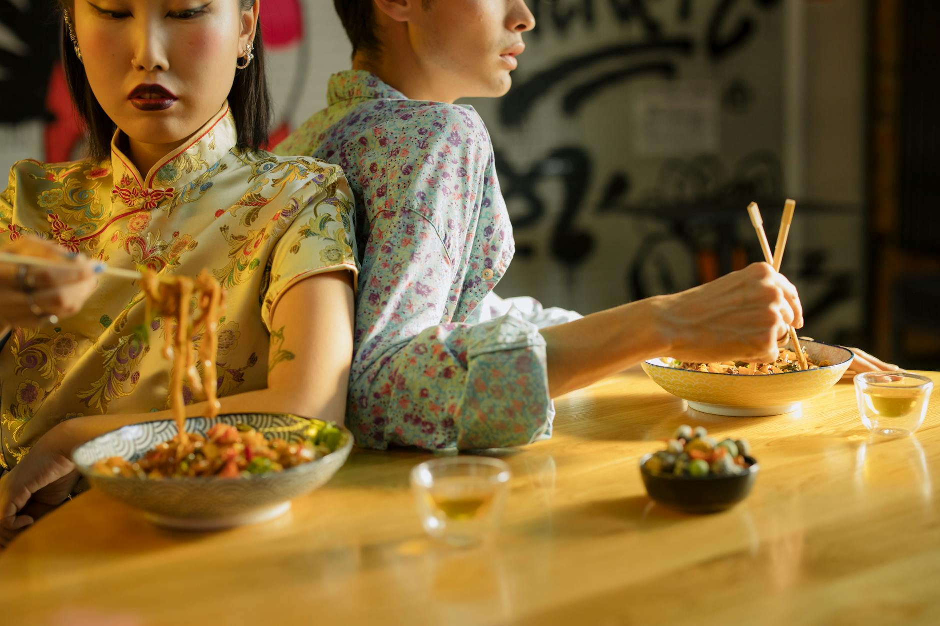 A couple dining together, enjoying Asian cuisine with chopsticks in a cozy restaurant setting.