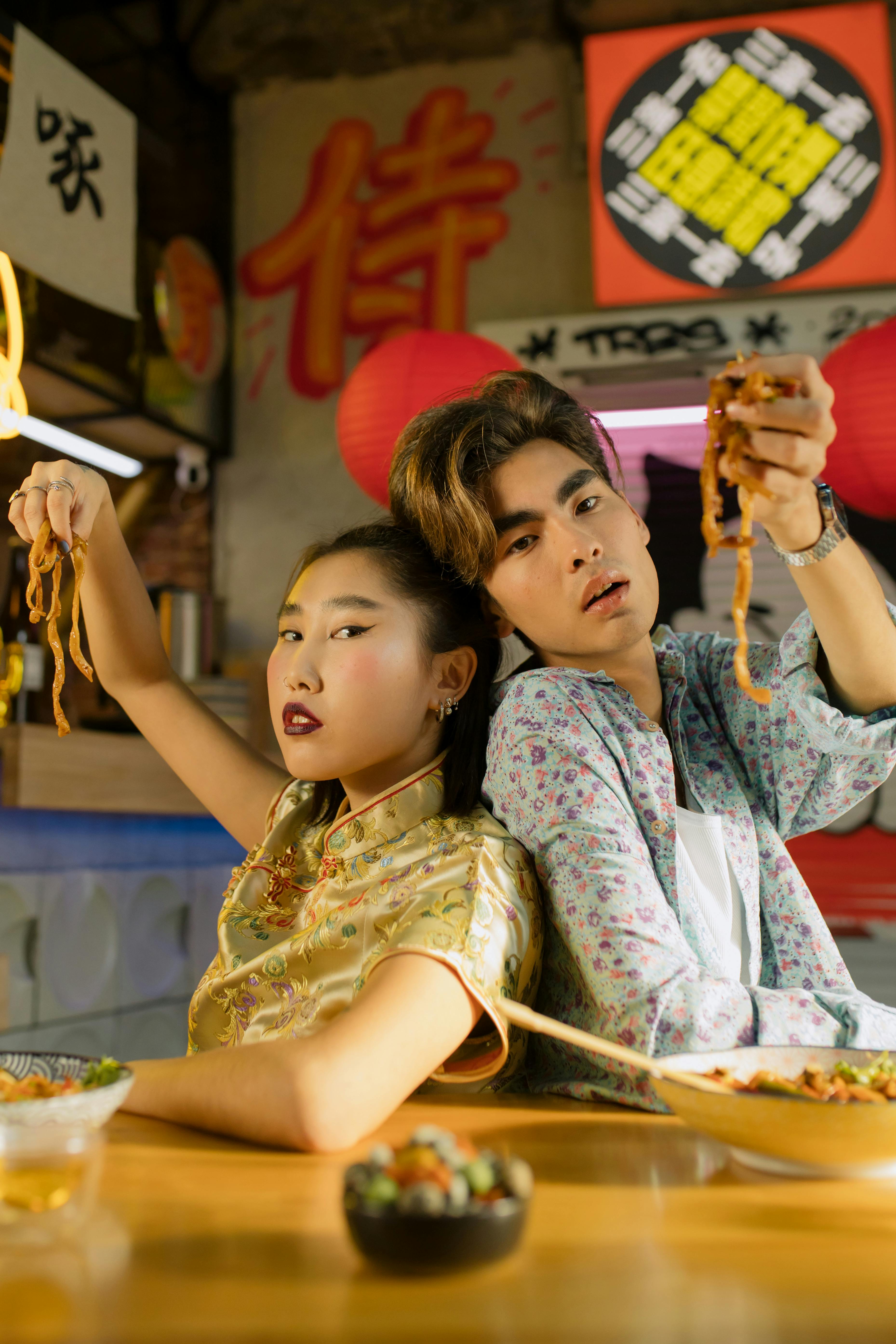 man and woman holding noodles with their hands