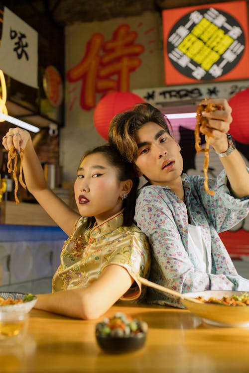 Man and Woman Holding Noodles with their Hands