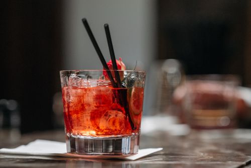 Free Refreshing iced red cocktail with garnish and straws on a bar table. Stock Photo