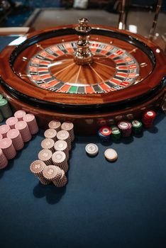 Roulette wheel on table with neatly stacked poker chips, capturing the essence of a casino.
