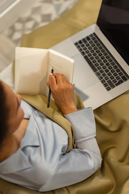 Free A Person Sitting on the Bed While using a Laptop Stock Photo