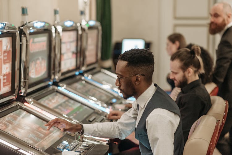 Men Playing Slot Machines In The Casino