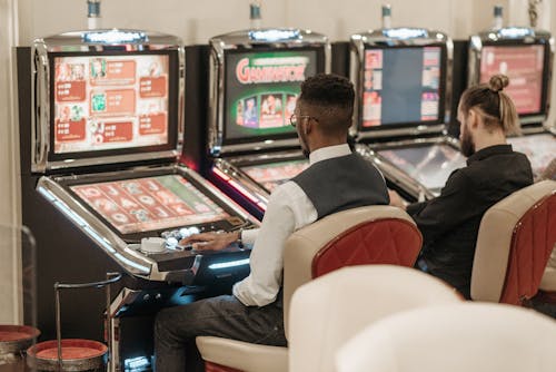 Free Men Sitting in Front of a Slot Machine Stock Photo