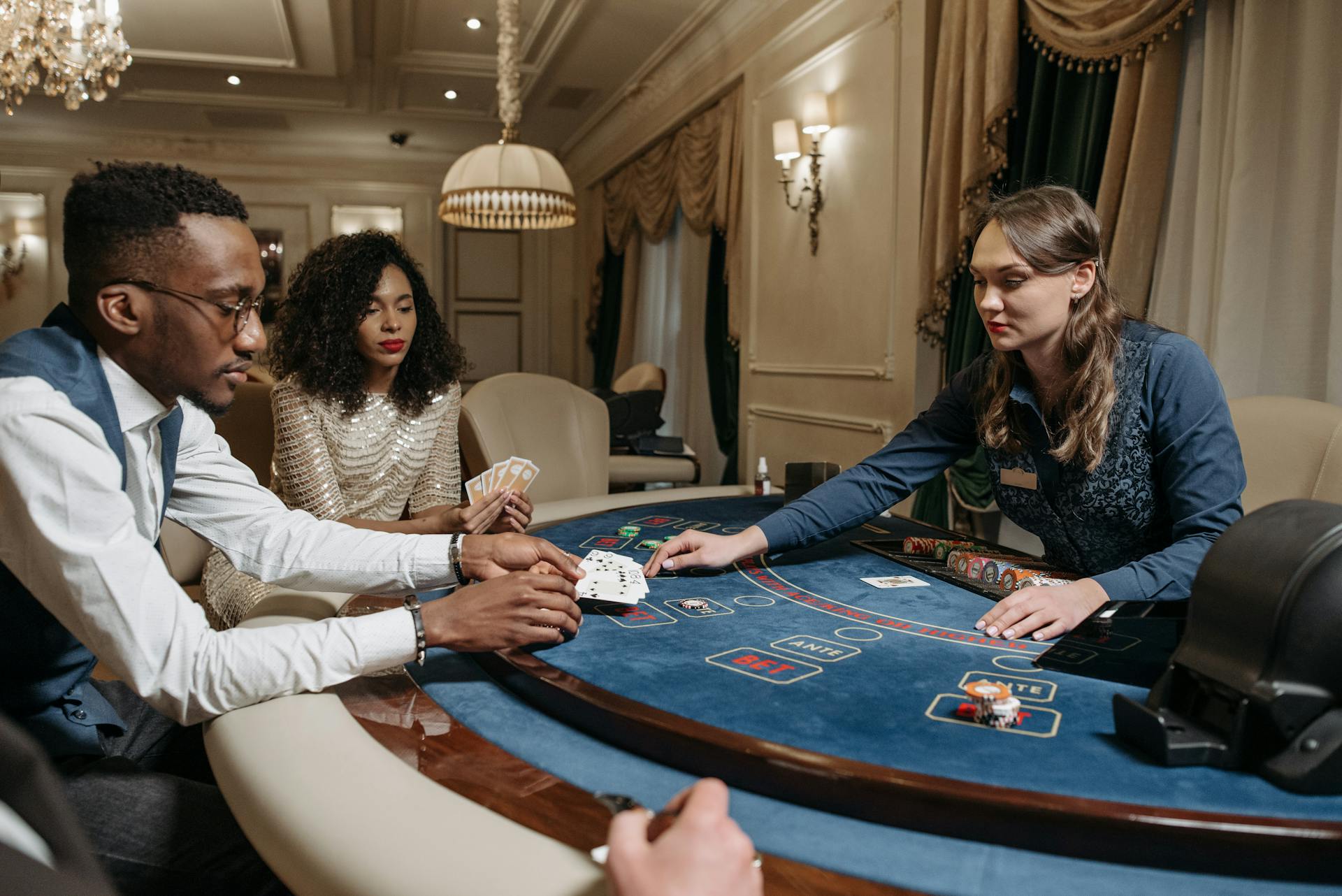 Players at a casino table engaged in a lively card game with poker chips and a dealer.