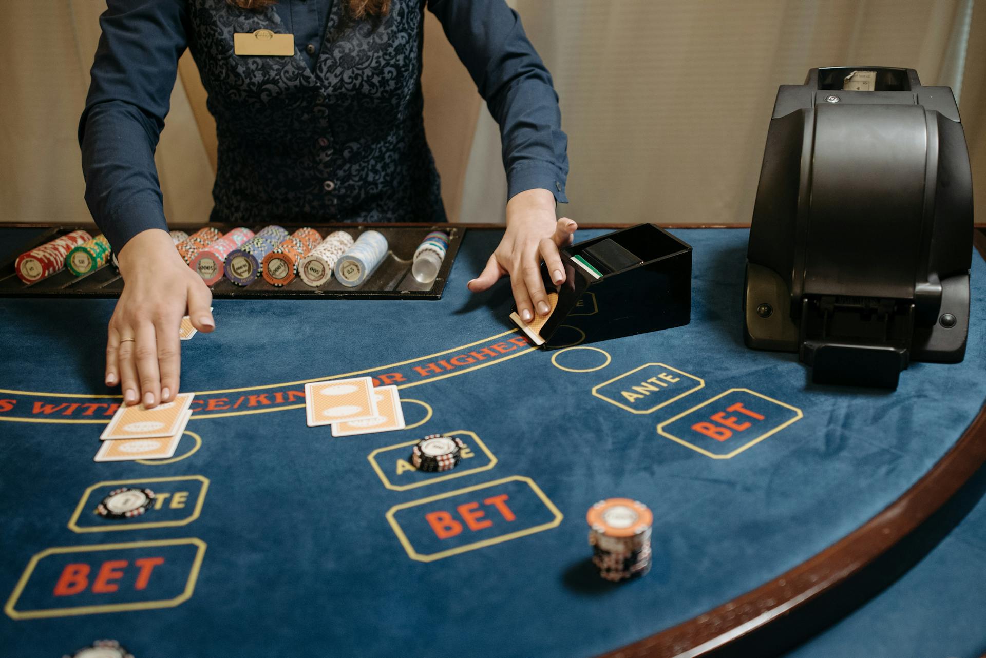 Casino dealer organizing cards and chips on a gaming table during a game.