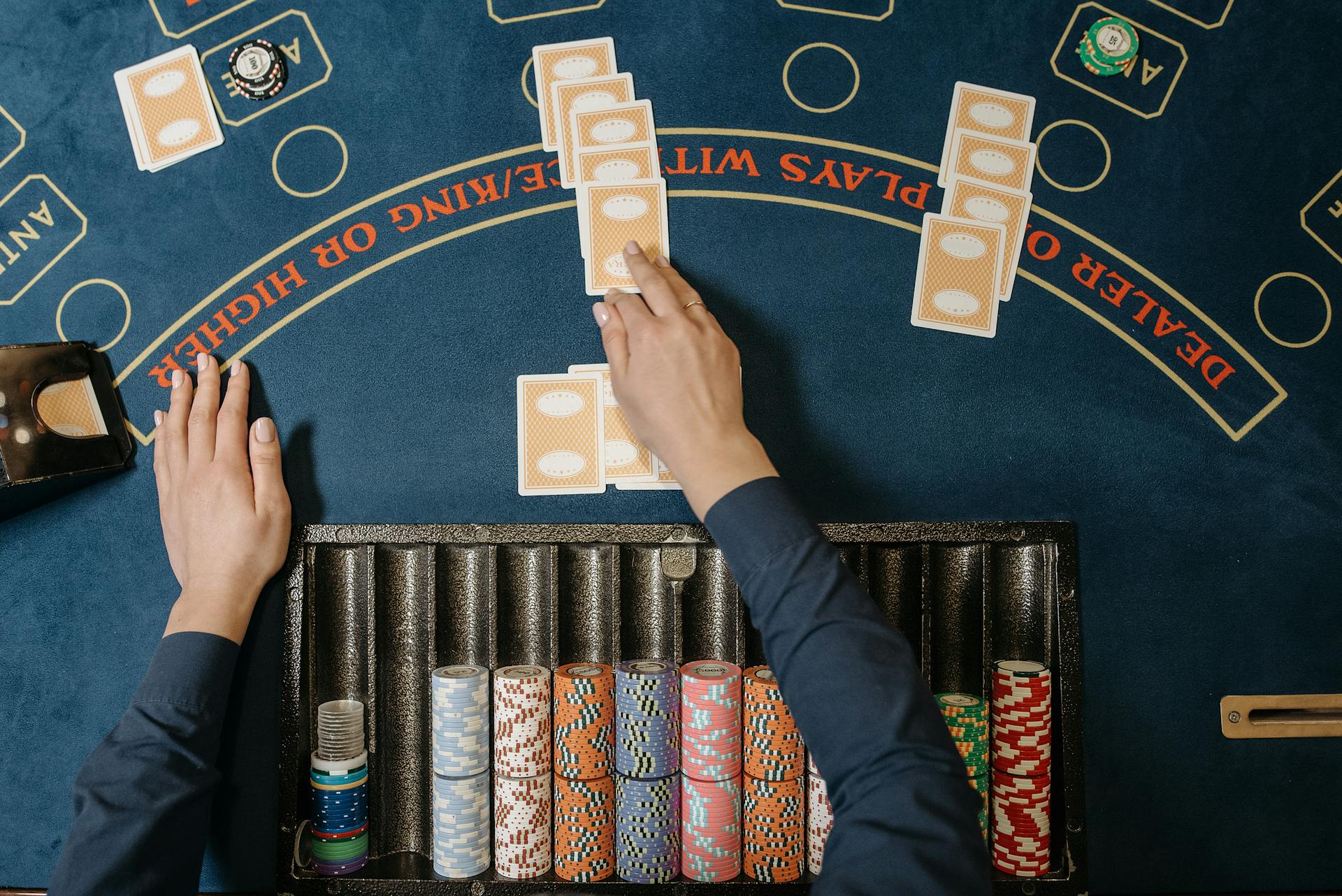 Dealer hands distributing cards at a casino blackjack table with chips in view.