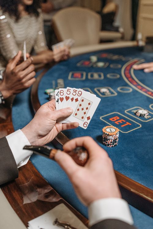 Free A close-up of players engaged in a poker game at a casino table, showcasing cards and chips. Stock Photo