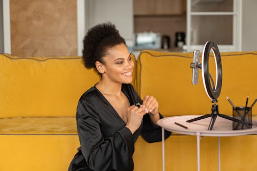 Smiling woman filming content using ring light and smartphone indoors.