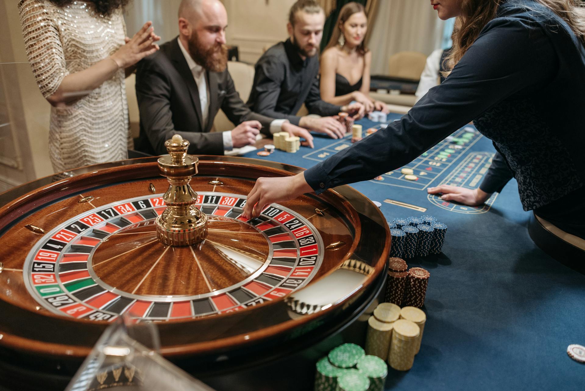 A vibrant casino scene shows players and a dealer engaging in a game of roulette.