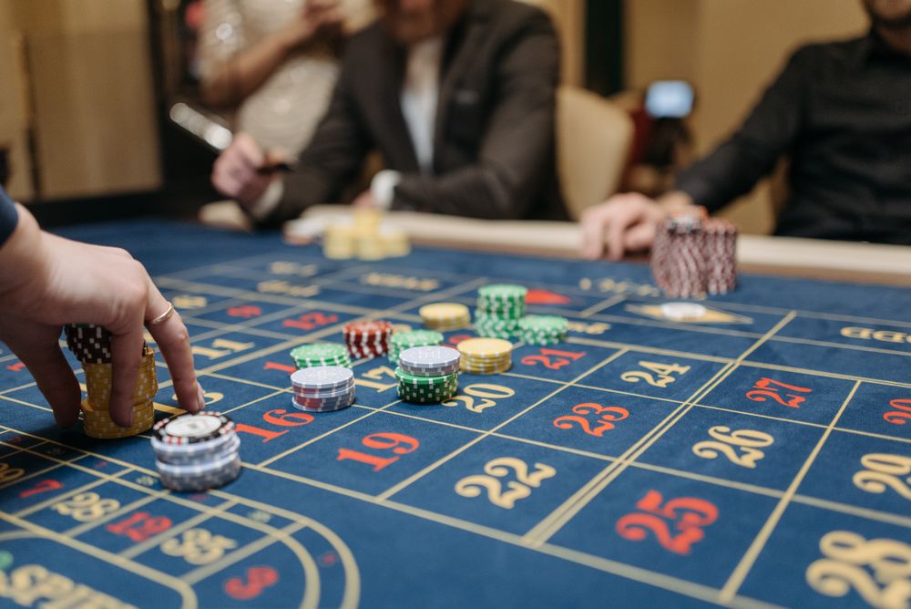 Tangan pemain memasang chip di meja roulette live casino