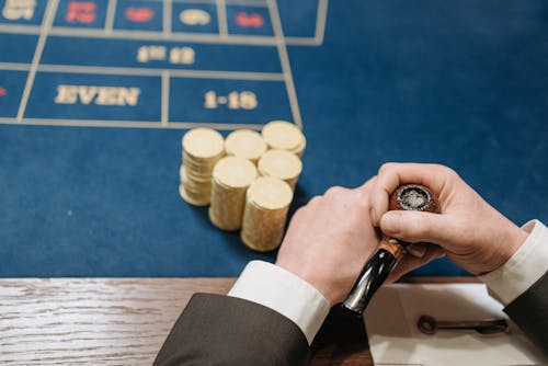 Person Holding Tobacco Pipe Beside Poker Chips 