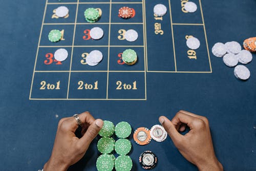 Free Hands arranging poker chips on a colorful casino gaming table, top view. Stock Photo