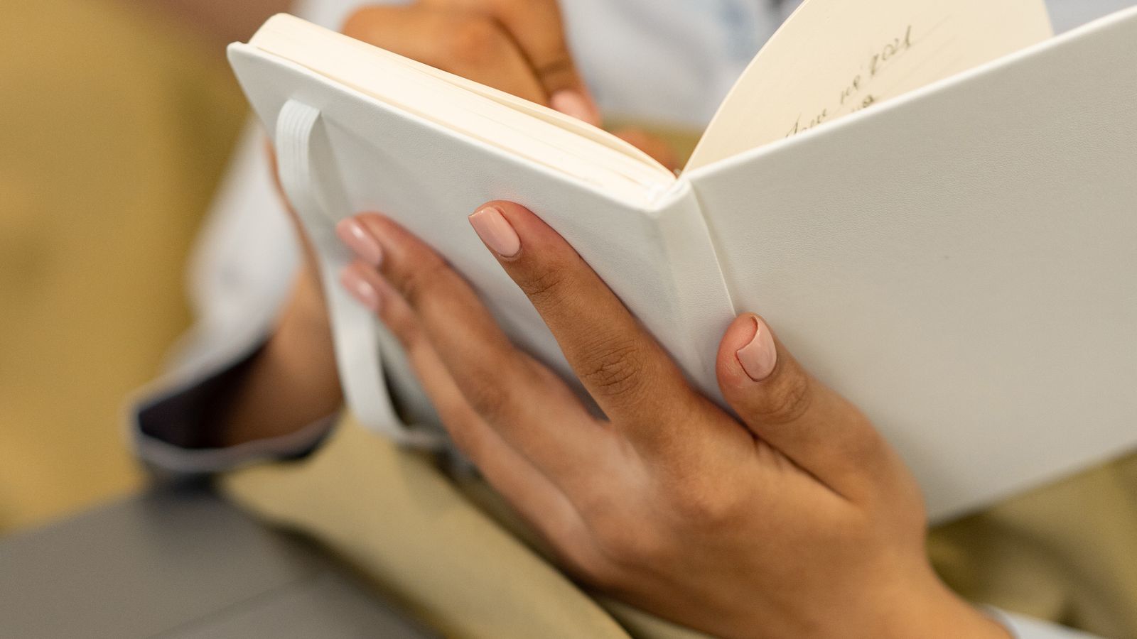 A woman writing in an open journal beside a laptop