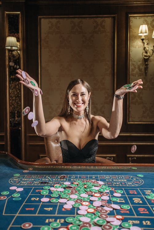 A Woman Sitting in front of a Gaming Table While Throwing Casino Chips