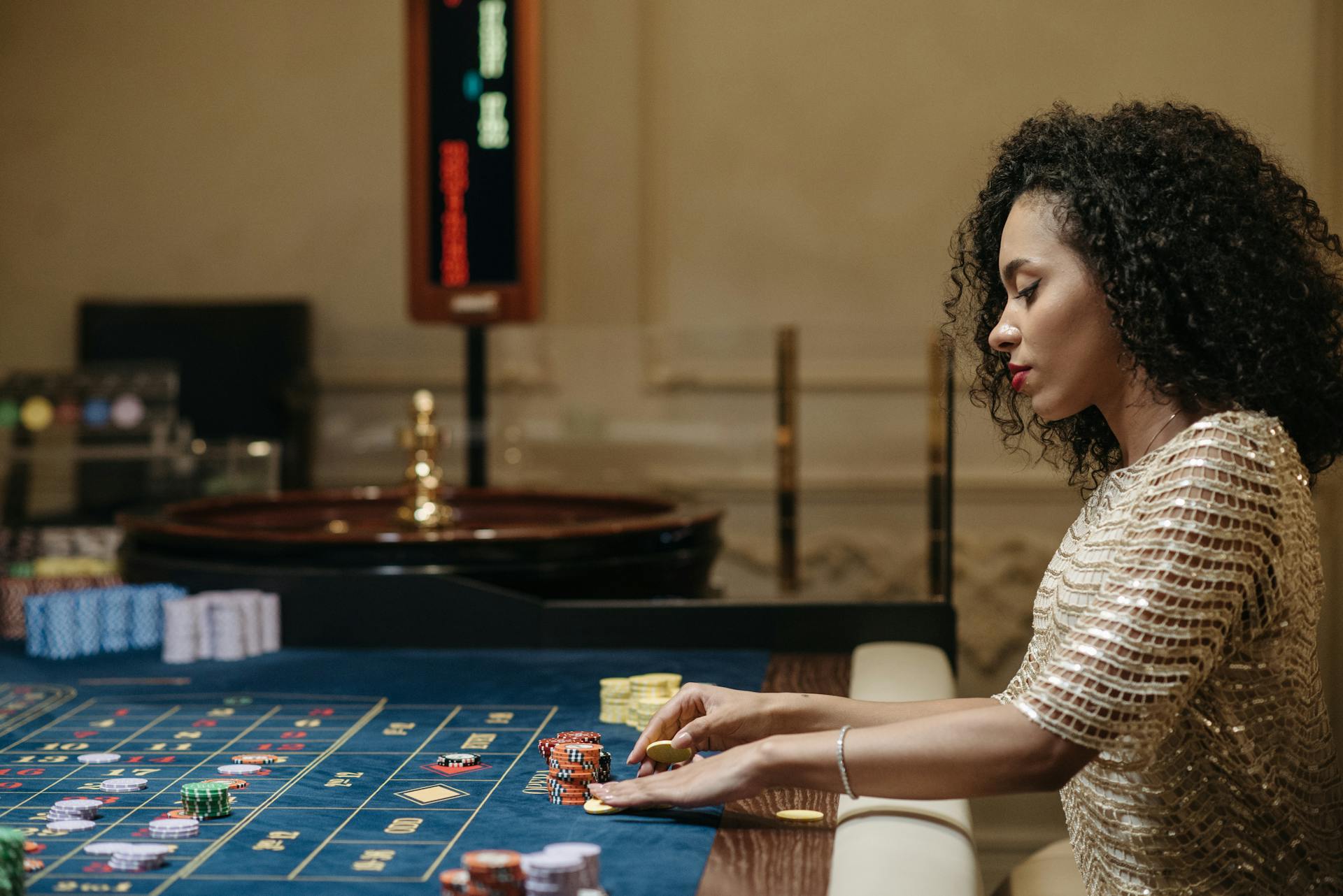 Stylish woman in a casino setting, playing roulette with stacks of chips.