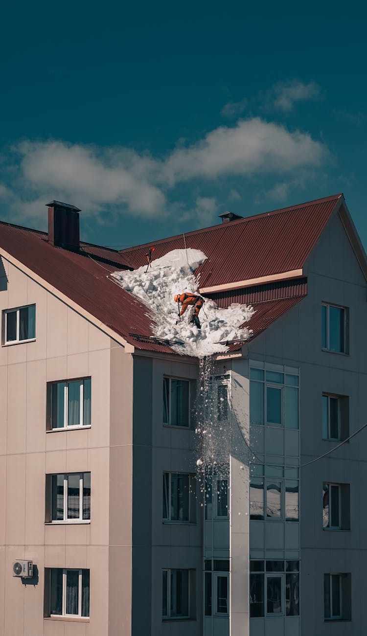 Men Cleaning Snow From Building Roof