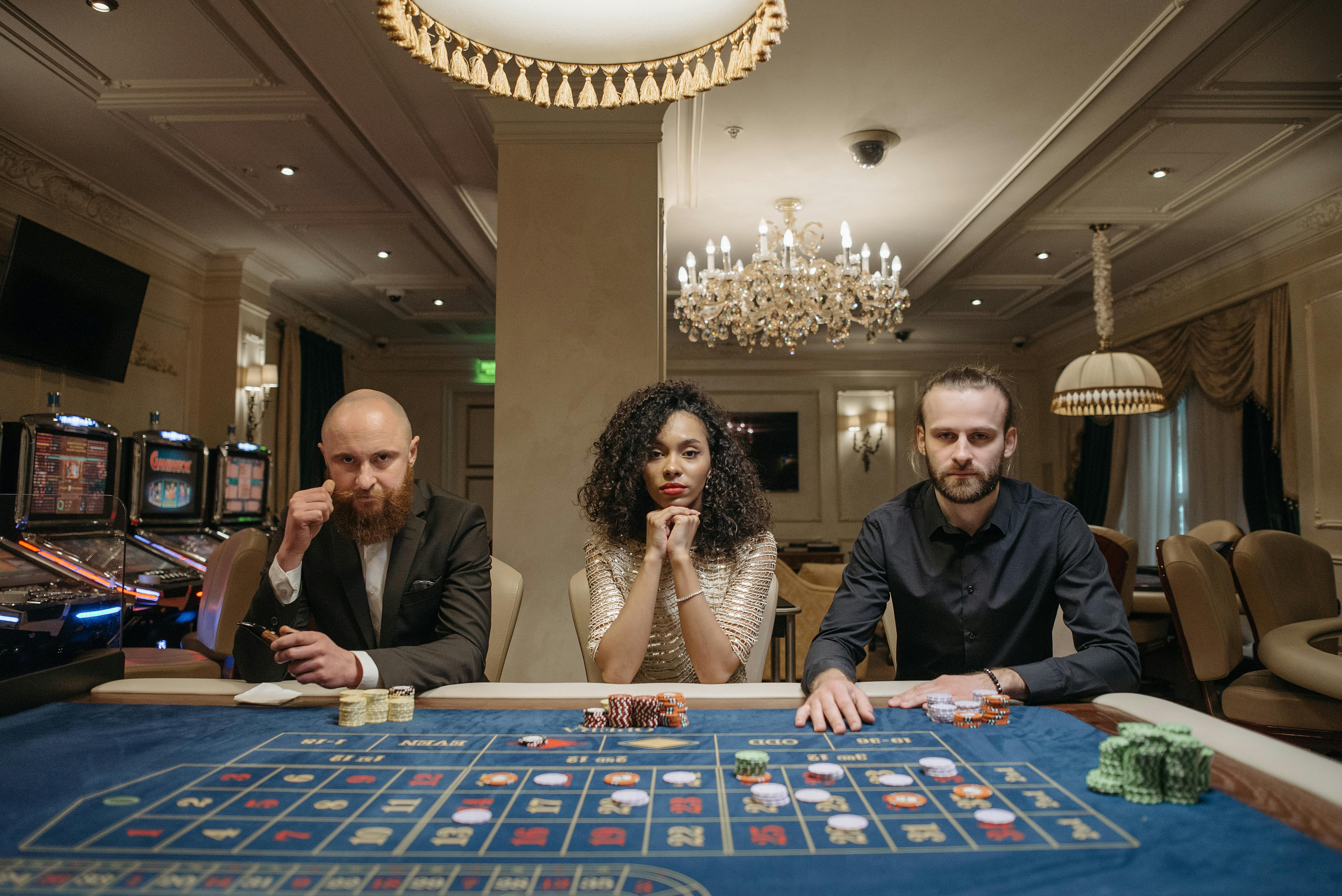 a woman and men sitting at a gaming table with stacks of casino tokens