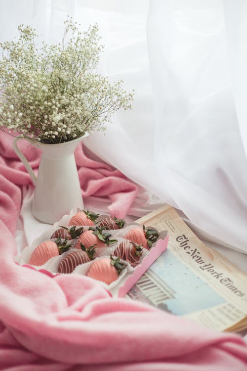 Baby's Breath Flower in White Ceramic Vase and a Box of Strawberry Flavored Chocolate