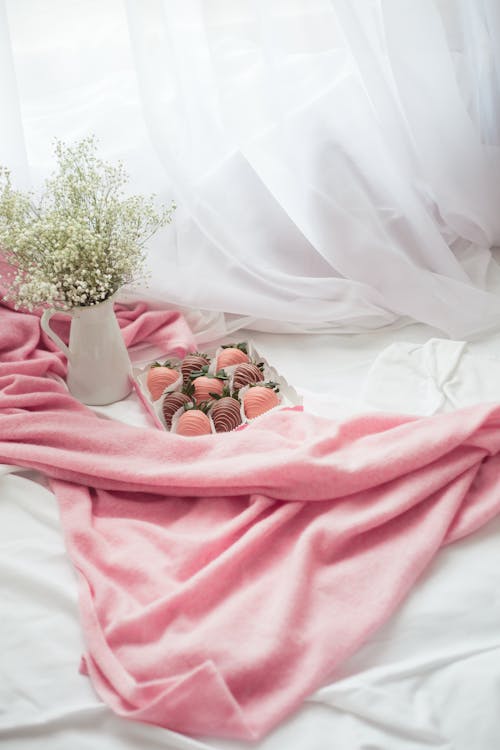 Baby's Breath Flower in White Ceramic Vase and a Box of Strawberry Flavored Chocolate