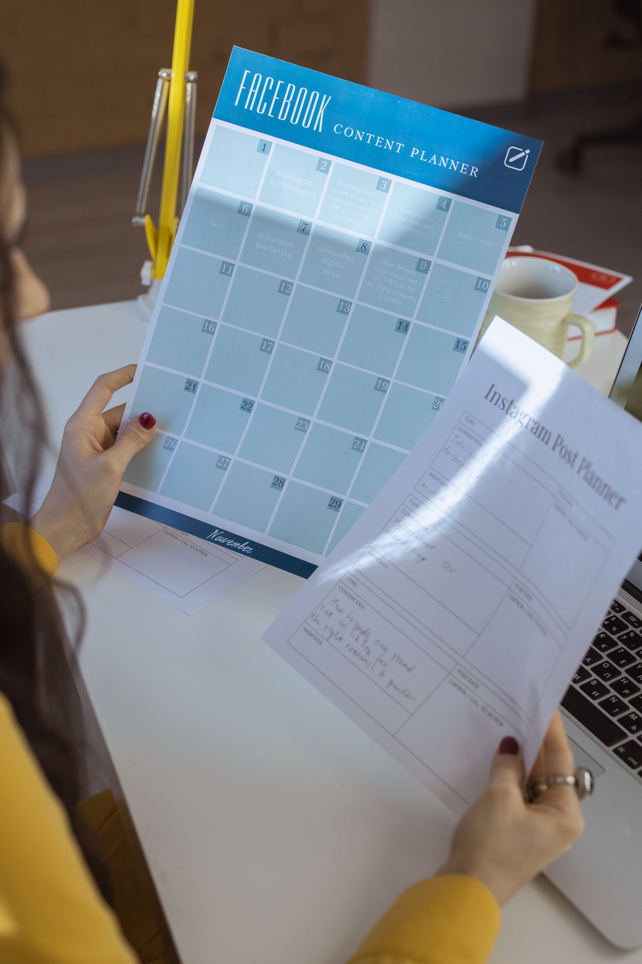 A focused workspace with planners, a laptop, and content planning materials