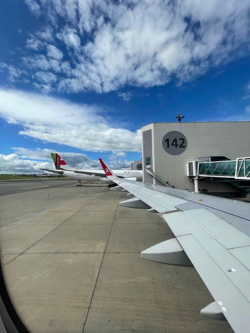 Free Airplane wing view at the airport gate, clear blue sky above. Ideal for travel and aviation themes. Stock Photo
