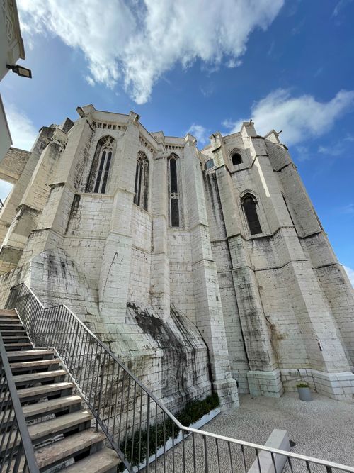 Free A stunning view of a Gothic church exterior with a staircase leading up, set against a bright blue sky. Stock Photo