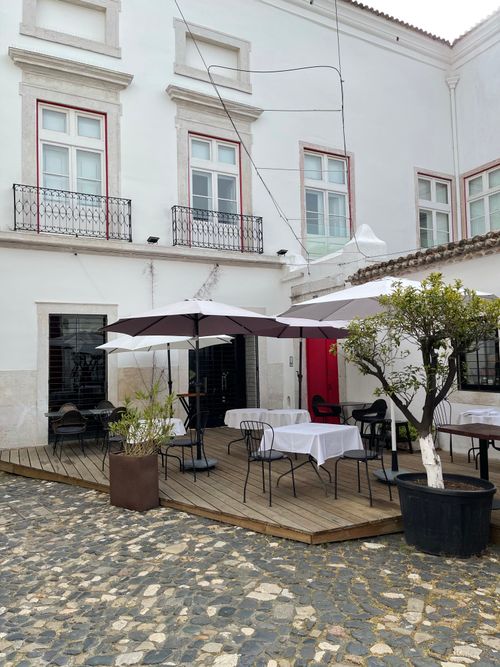 Free Outdoor café seating with umbrellas on a stone terrace, perfect for a relaxing autumn day. Stock Photo