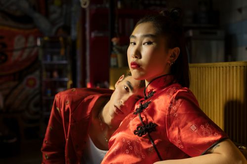 Free A fashionable couple in vibrant traditional Chinese attire posing indoors with dramatic lighting. Stock Photo