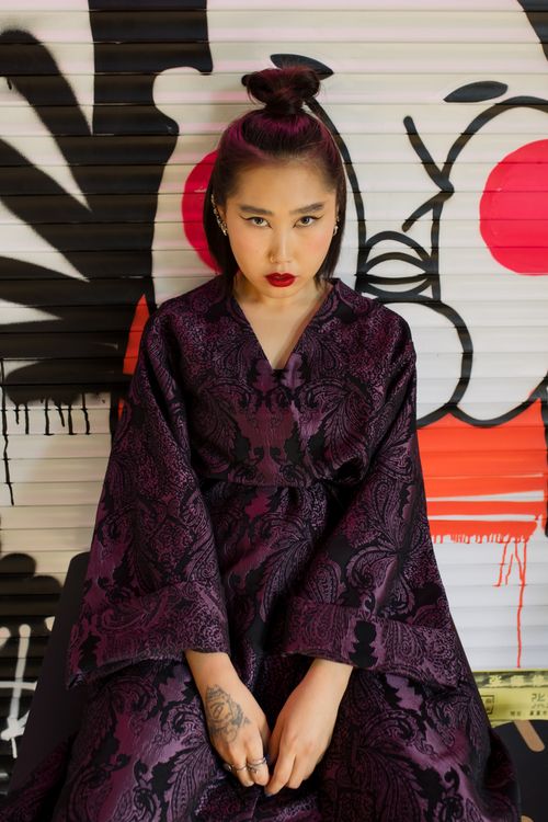 Free Fashion-forward woman in a purple kimono poses against vibrant graffiti art. Stock Photo