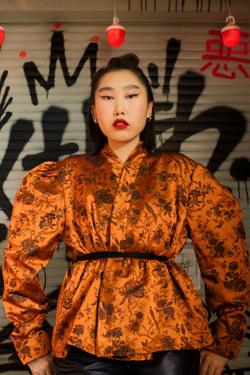 Free Stylish Asian woman posing in a floral kimono in front of vibrant graffiti art. Stock Photo