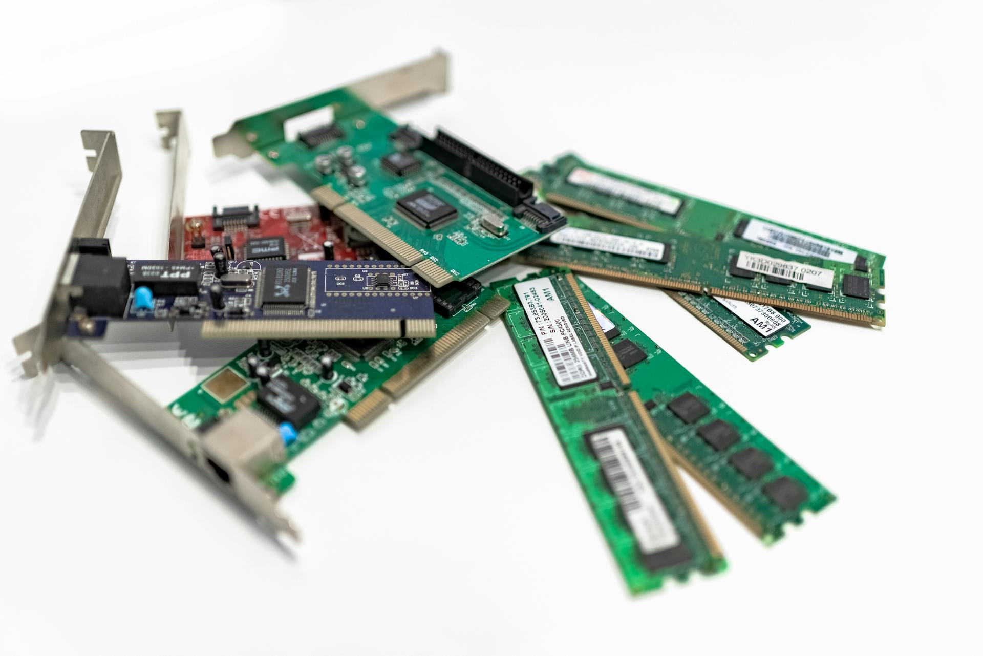 A detailed close-up of computer RAM sticks and PCI cards arranged on a white surface for tech illustration.