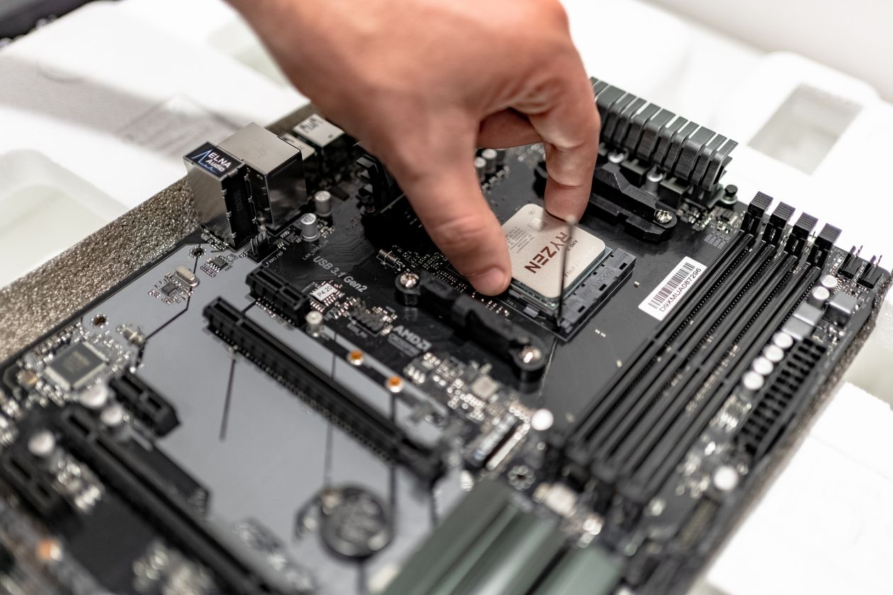 Một bàn tay đặt con chip CPU vào ổ cắm trên bo mạch chủ màu đen