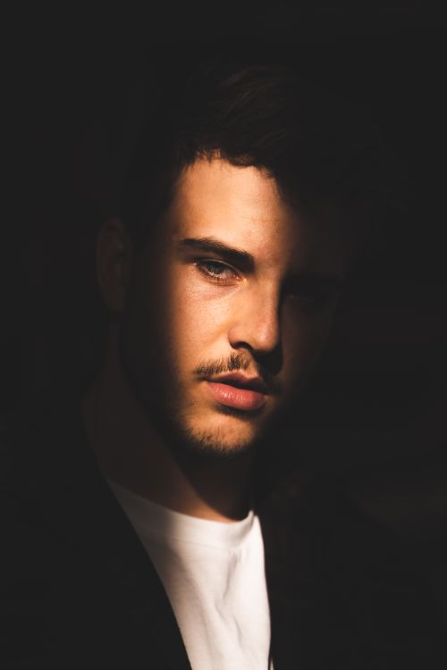 Free Artistic close-up portrait of a young man in dramatic lighting, creating a moody and introspective vibe. Stock Photo