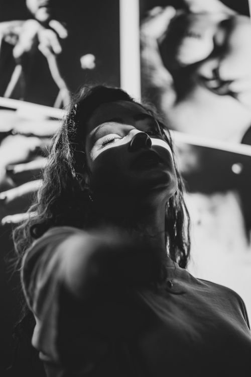 Free Striking monochrome portrait of a woman with dramatic shadows in a reflective pose. Stock Photo