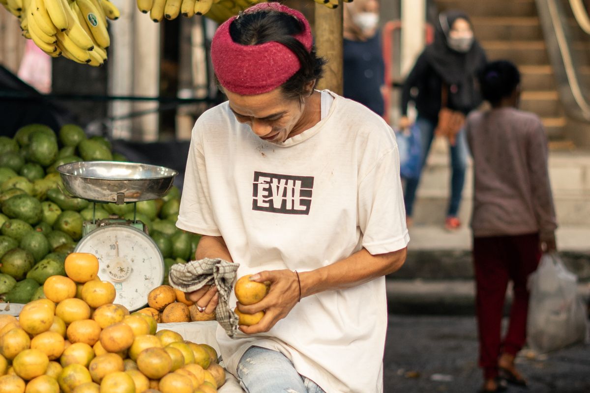 Vendedor ordenando naranjas en un puesto de frutas del mercado