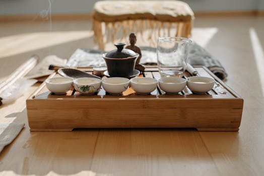 A peaceful tea ceremony setup featuring a Buddha figurine and teacups on a wooden tray.